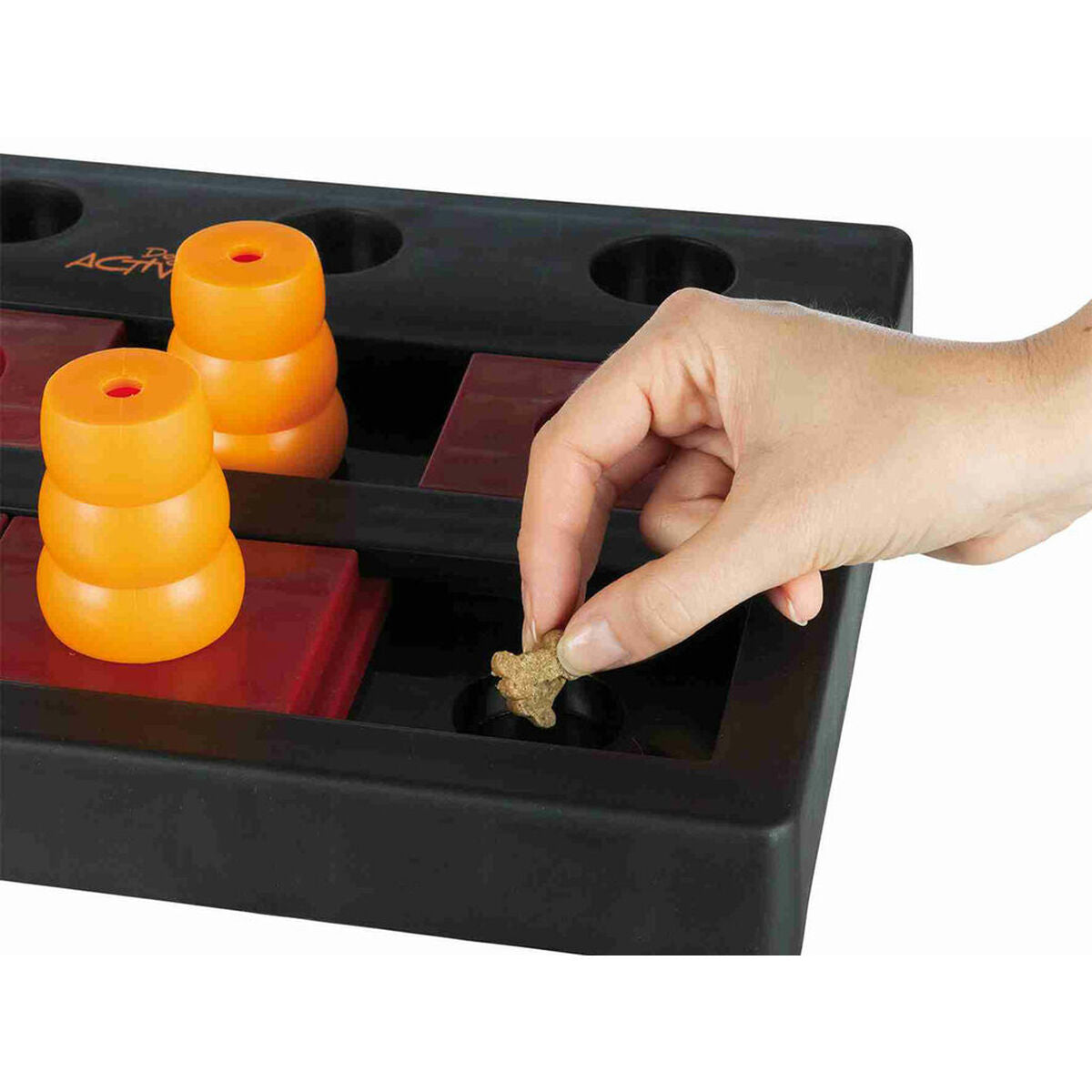 Hand legt einen Snack in eine Vertiefung des Chess-Spielbretts neben orangefarbenen Kegeln