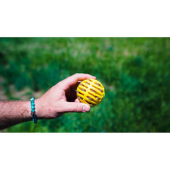 Hand hält den gelben Flingerz-Ball mit Öffnungen im Freien