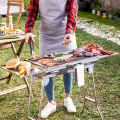 ExelQ-Edelstahlgrill mit Grillgut und ausgeklappten seitlichen Ablagen im Garten