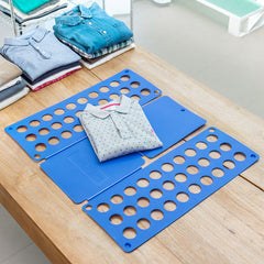Blaues Wäschefaltbrett auf einem Tisch mit gefaltetem Hemd und weiteren Kleidungsstücken