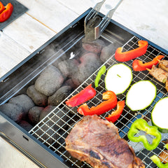 Holzkohle wird bei abgenommenem Grillrost im BearBQ-Grill nachgelegt