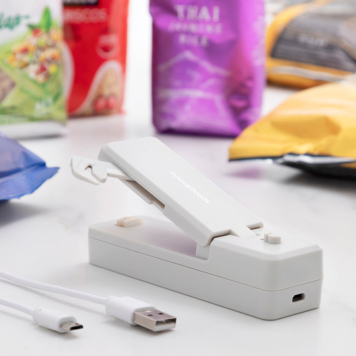 Geöffneter grauer InnovaGoods Rebasyl auf einer Arbeitsfläche neben USB-auf-Micro-USB-Ladekabel