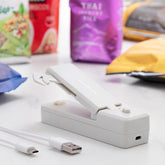 Geöffneter grauer InnovaGoods Rebasyl auf einer Arbeitsfläche neben USB-auf-Micro-USB-Ladekabel