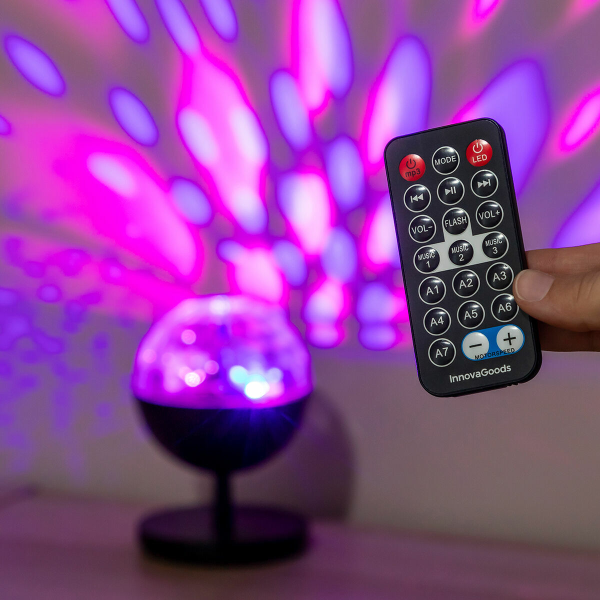 Hand hält die Istarlyt-Fernbedienung vor einer violetten Lichtprojektion