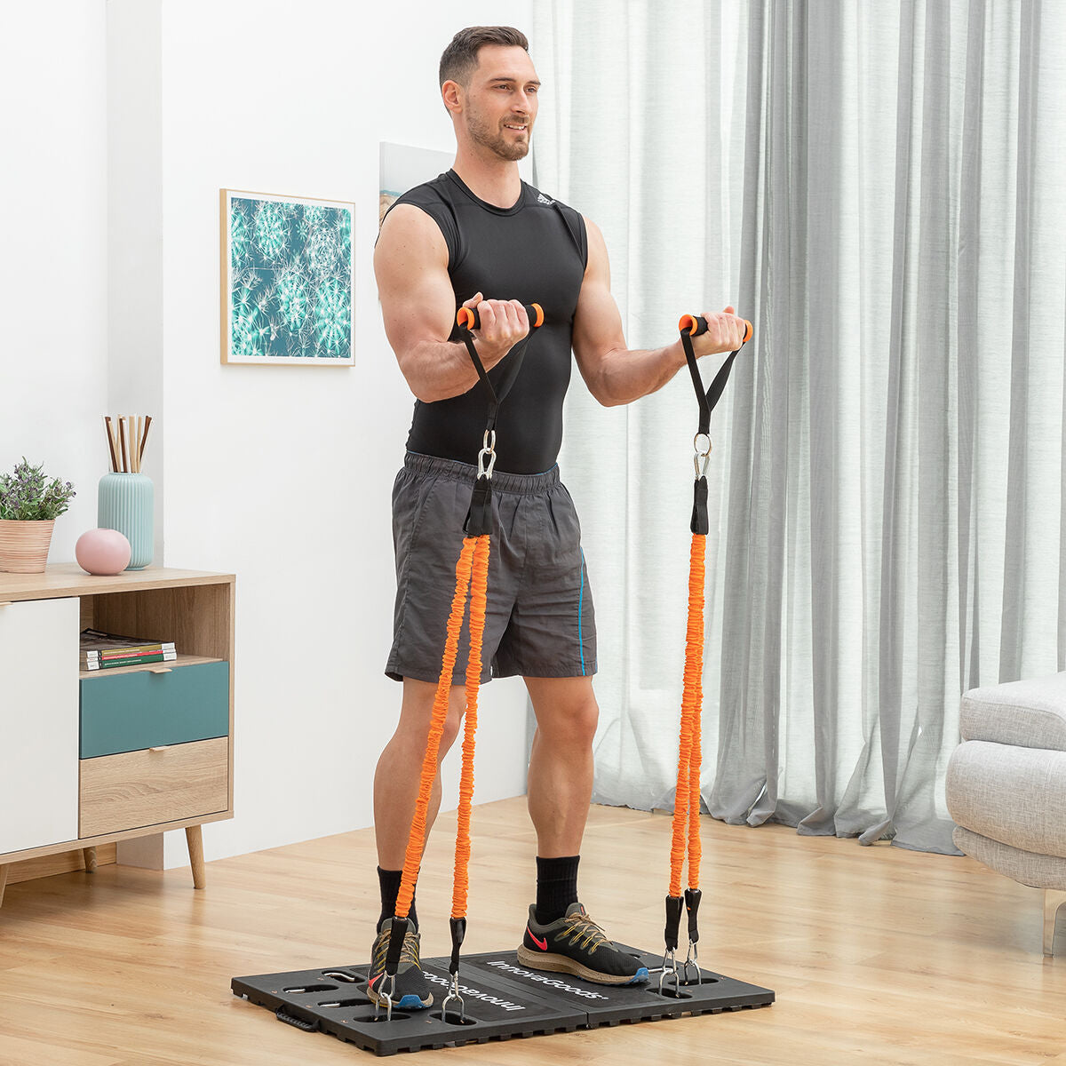 Gympak-Max-Basis mit zwei Handgriffen und orangefarbenen Widerstandsbändern bei einer Übung