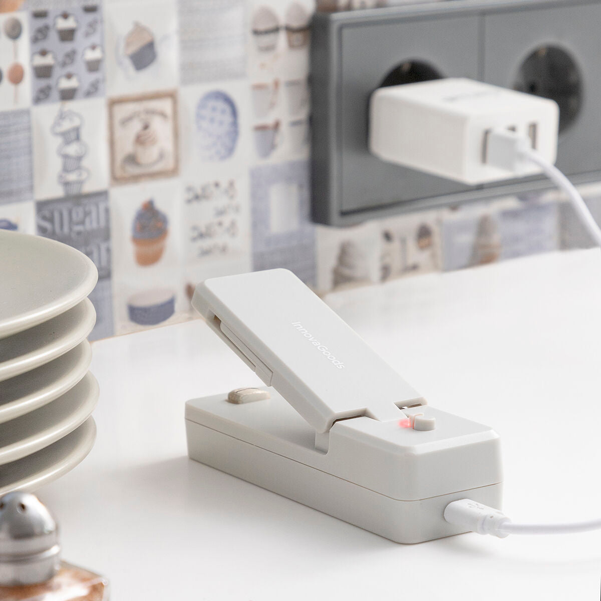 Grauer InnovaGoods Rebasyl mit geöffnetem Oberteil beim Laden über USB-Kabel an einer separaten Stromquelle